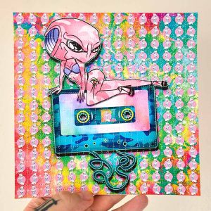 photo of a hand holding alien themed lsd blotter art gift featuring psychedelic rainbow colours and classic audio cassette tape