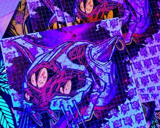 photo of LSD blotter art print exposed to black light featuring a cat with an acid tab on its tongue